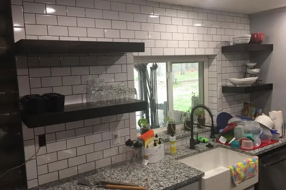 Subway tile backsplash with black floating shelves and farmhouse sink, C&A Roofing & Construction