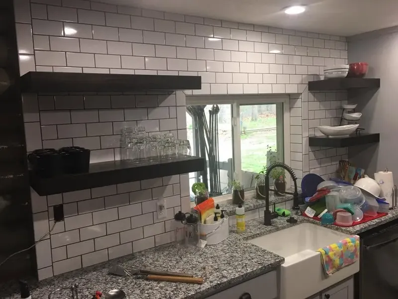 Subway tile backsplash with black floating shelves and farmhouse sink, C&A Roofing & Construction