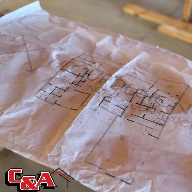 Crumpled floor plan blueprints on table, C&A Roofing & Construction