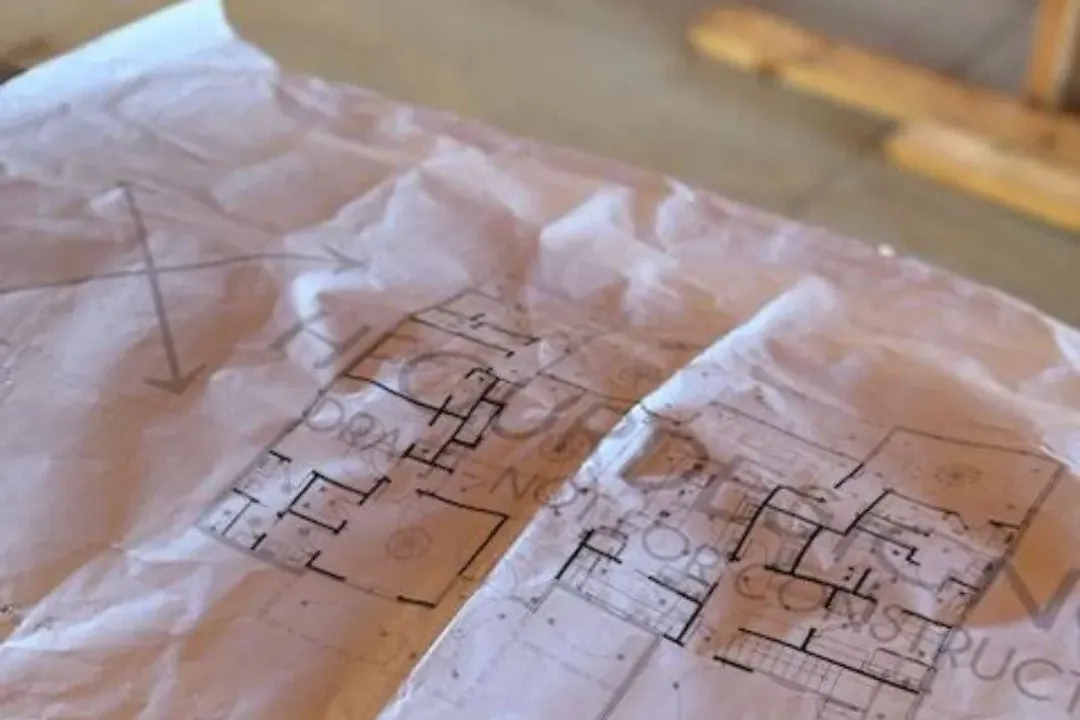 Crumpled floor plan blueprints on table, C&A Roofing & Construction