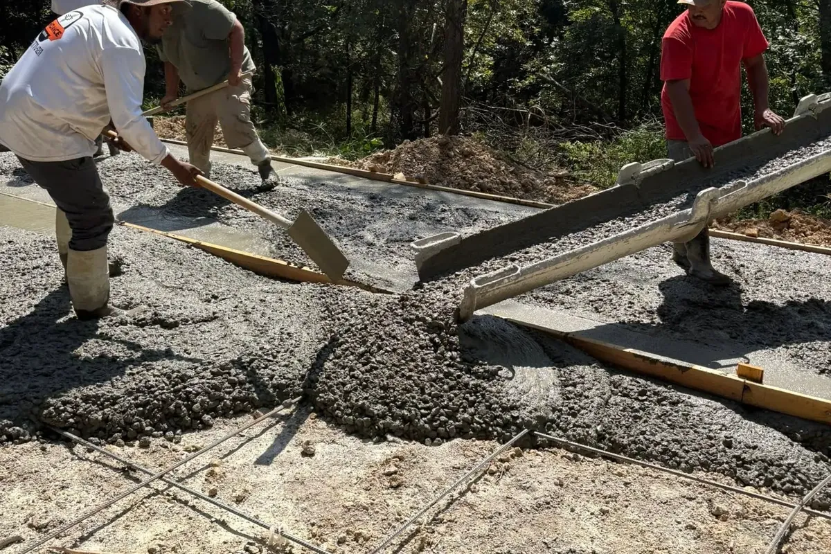 Crew spreading and screeding fresh concrete slab over rebar, C&A Roofing & Construction