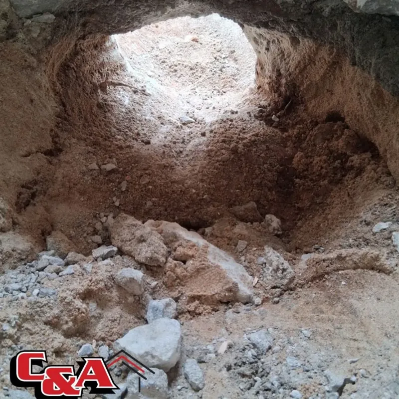 Close-up of dug excavation hole in red dirt and rock, C&A Roofing & Construction
