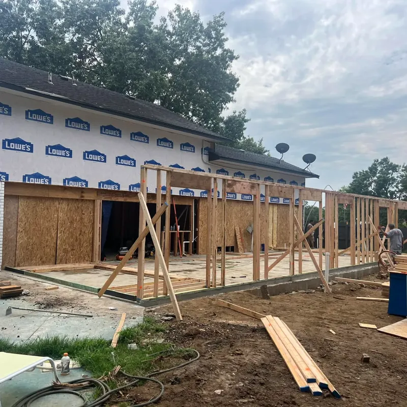 Framing addition on Lowe's-wrapped house, dumpster beside, C&A Roofing & Construction