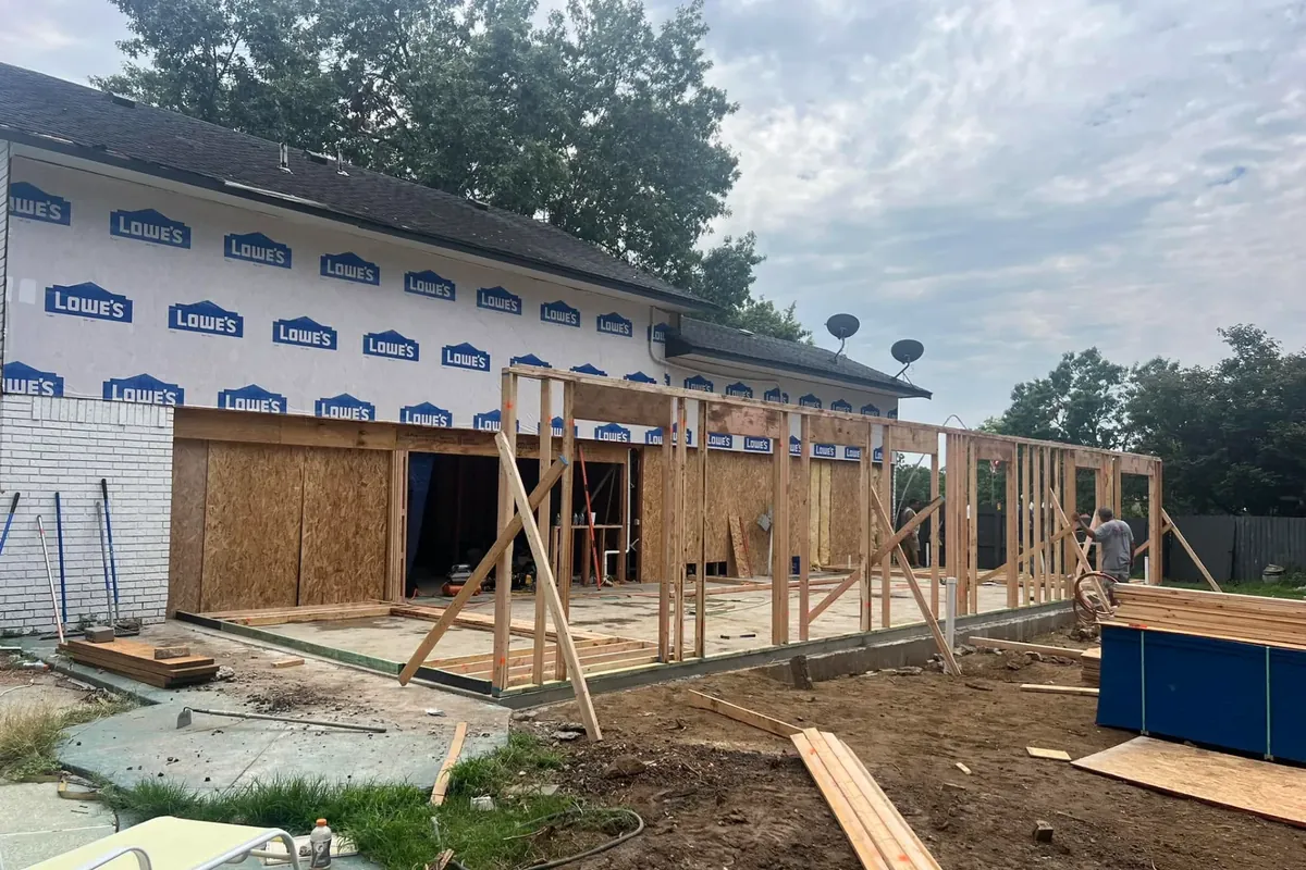 Framing addition on Lowe's-wrapped house, dumpster beside, C&A Roofing & Construction