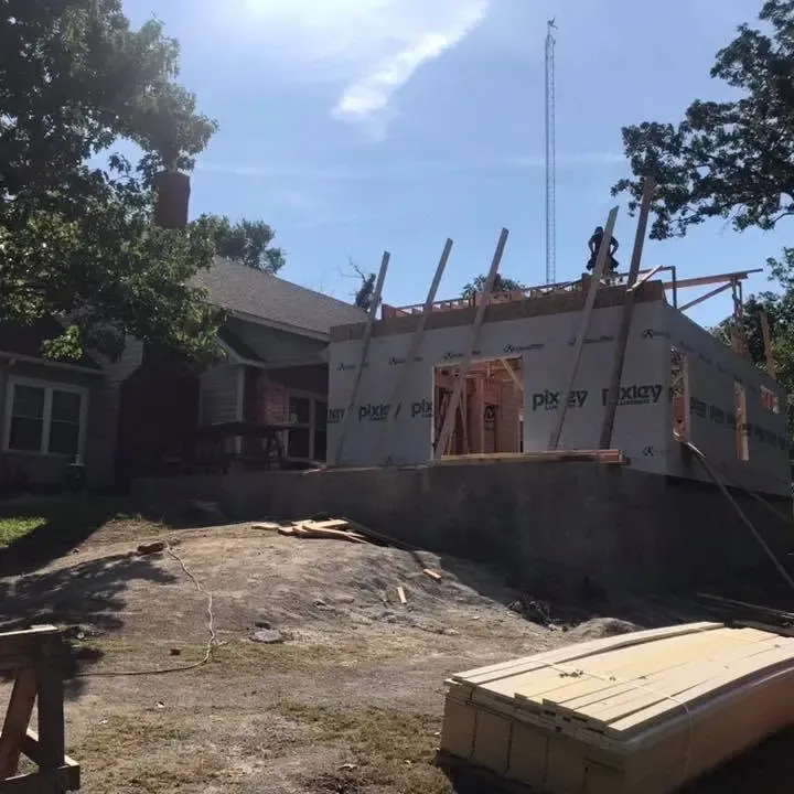 Addition framing on stone house against bright sky, C&A Roofing & Construction