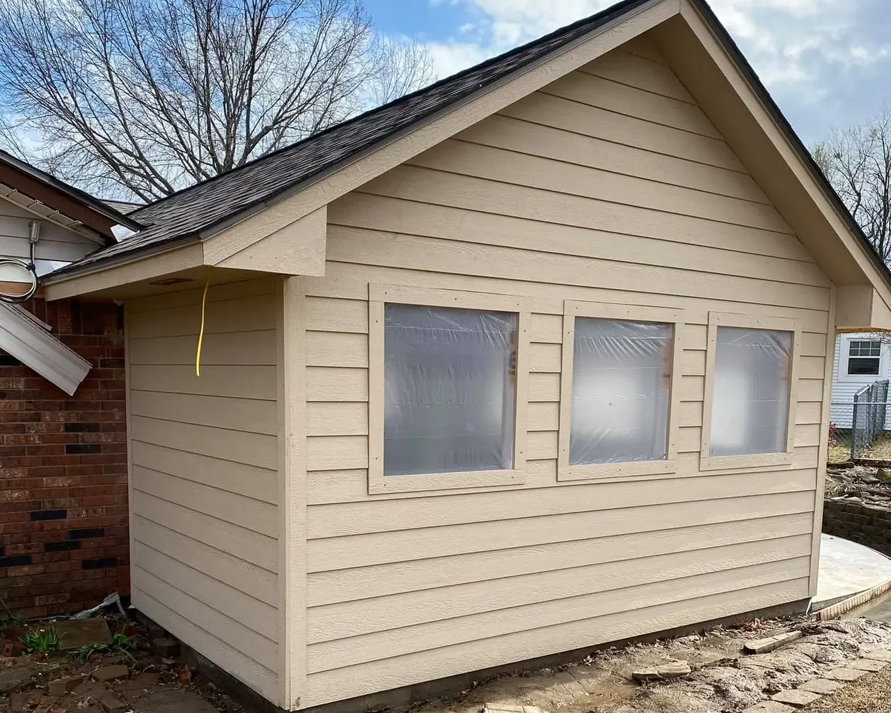 New tan-sided addition with shingle roof attached to brick house, C&A Roofing & Construction