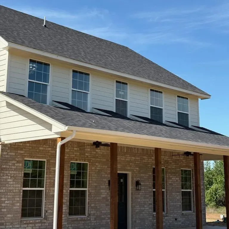 New two-story house, dark shingle roof, light siding, brick porch, C&A Roofing & Construction
