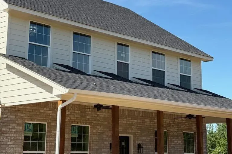 New two-story house, dark shingle roof, light siding, brick porch, C&A Roofing & Construction