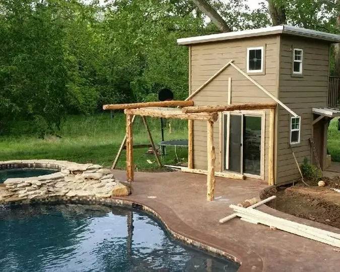 Small pool house with log pergola beside freeform pool, C&A Roofing & Construction