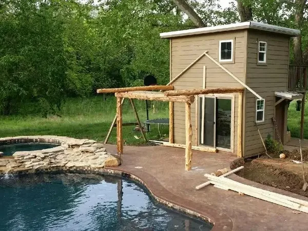 Small pool house with log pergola beside freeform pool, C&A Roofing & Construction