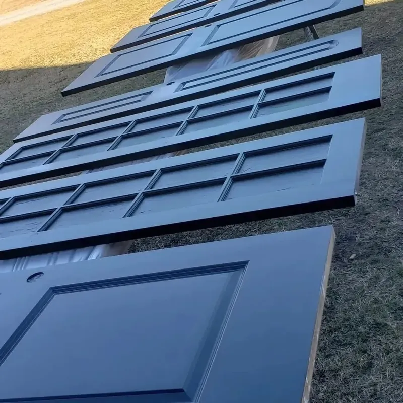 Row of freshly painted navy panel doors drying on grass, C&A Roofing & Construction