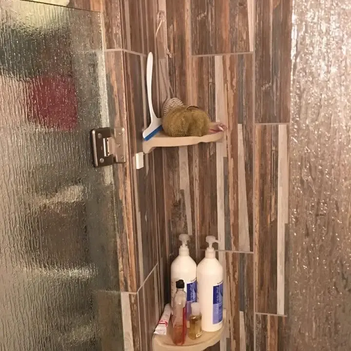 Wood-look tile shower wall with corner shelves and toiletries, C&A Roofing & Construction