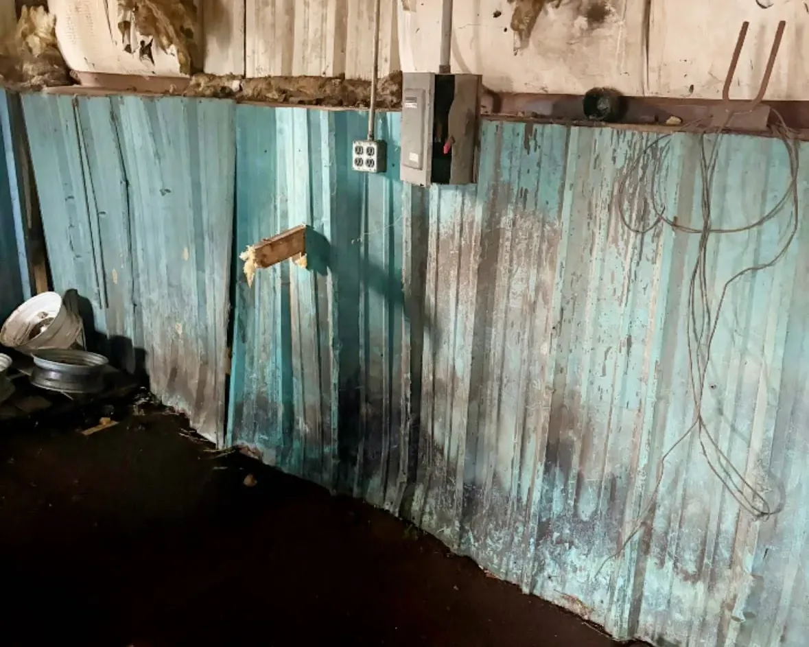 Damaged interior wall paneling with stained flooring, C&A Roofing & Construction