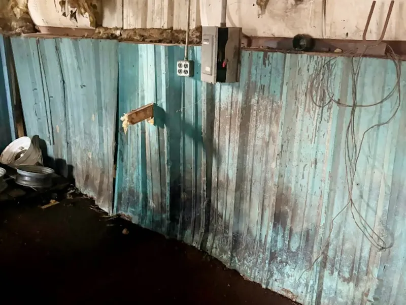 Damaged interior wall paneling with stained flooring, C&A Roofing & Construction