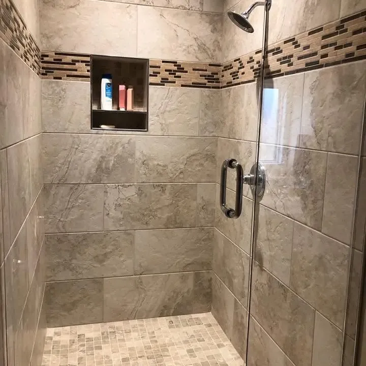 Tiled walk-in shower with accent band, niche and glass door, C&A Roofing & Construction