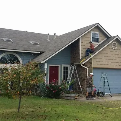Two-story house with crew on ladder at gutter line, C&A Roofing & Construction