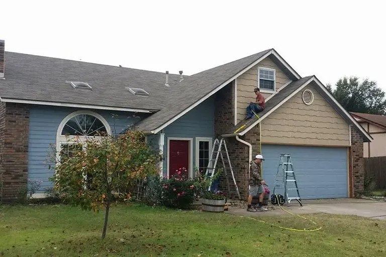 Two-story house with crew on ladder at gutter line, C&A Roofing & Construction
