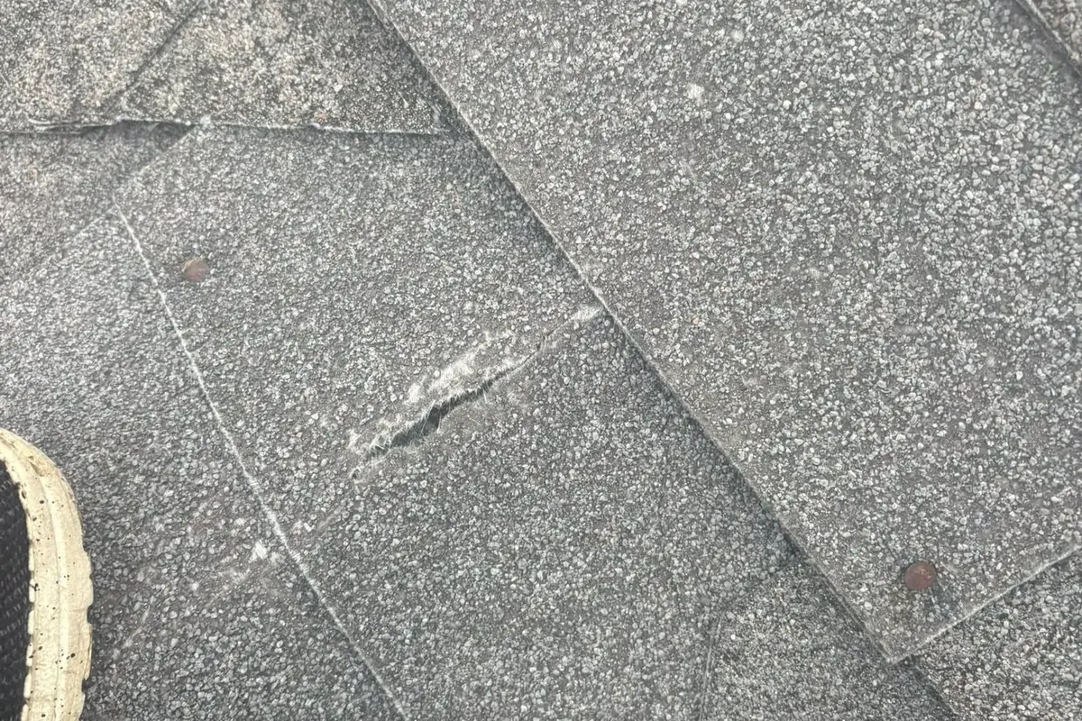 Close-up of torn gray asphalt shingle, C&A Roofing & Construction