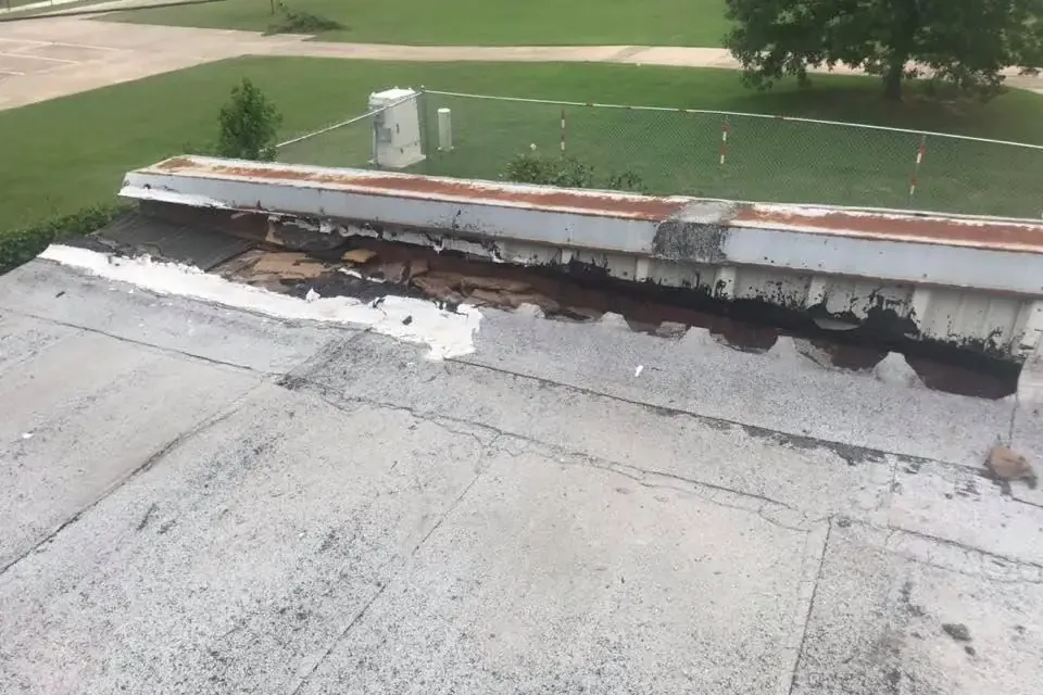 Flat roof edge with torn membrane and damaged parapet, C&A Roofing & Construction