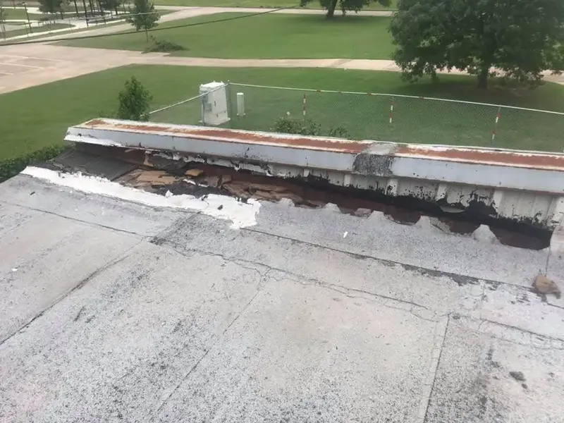 Flat roof edge with torn membrane and damaged parapet, C&A Roofing & Construction