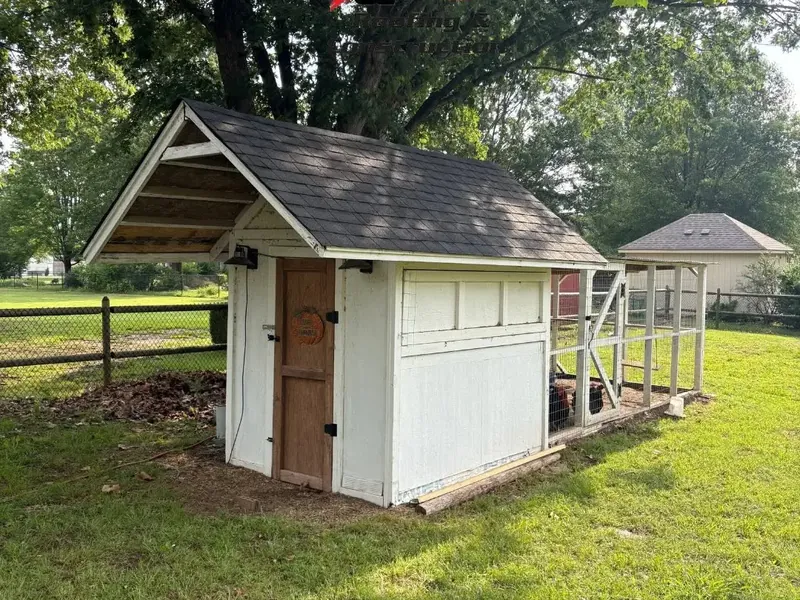 Small white shed with new asphalt shingle roof in yard, C&A Roofing & Construction