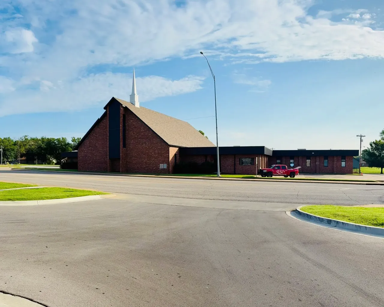 Wide shot of brick church with new shingle roof, C&A truck, C&A Roofing & Construction