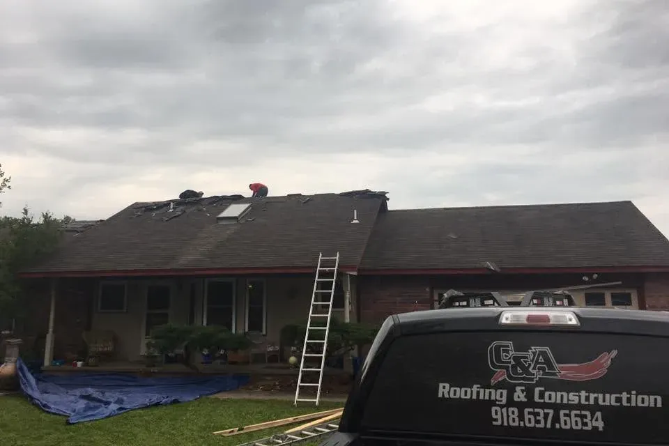 Brick ranch house roof job, branded C&A truck in foreground, C&A Roofing & Construction