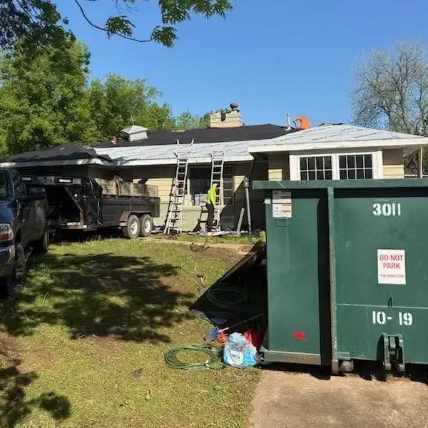 House with ladders and large green dumpster in yard, C&A Roofing & Construction