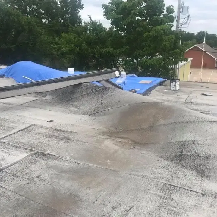 Damaged commercial flat roof with blue tarps, C&A Roofing & Construction