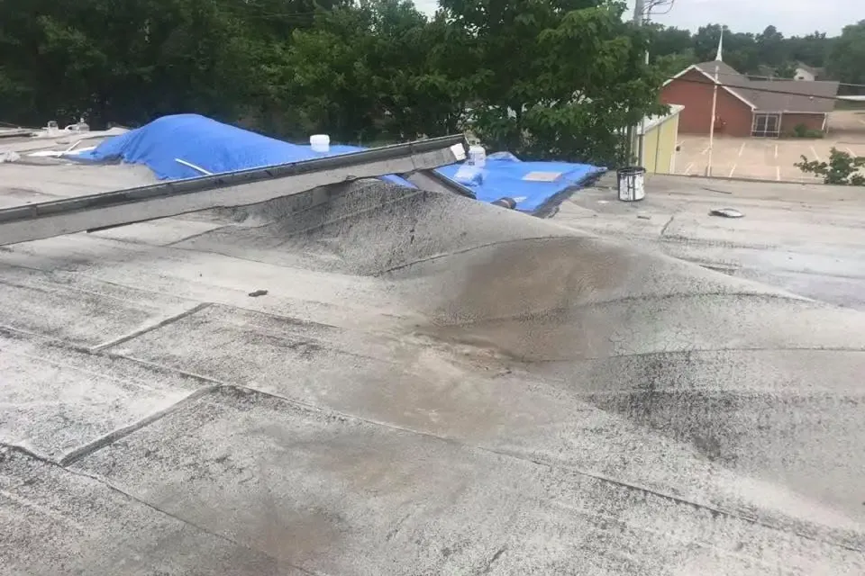 Damaged commercial flat roof with blue tarps, C&A Roofing & Construction