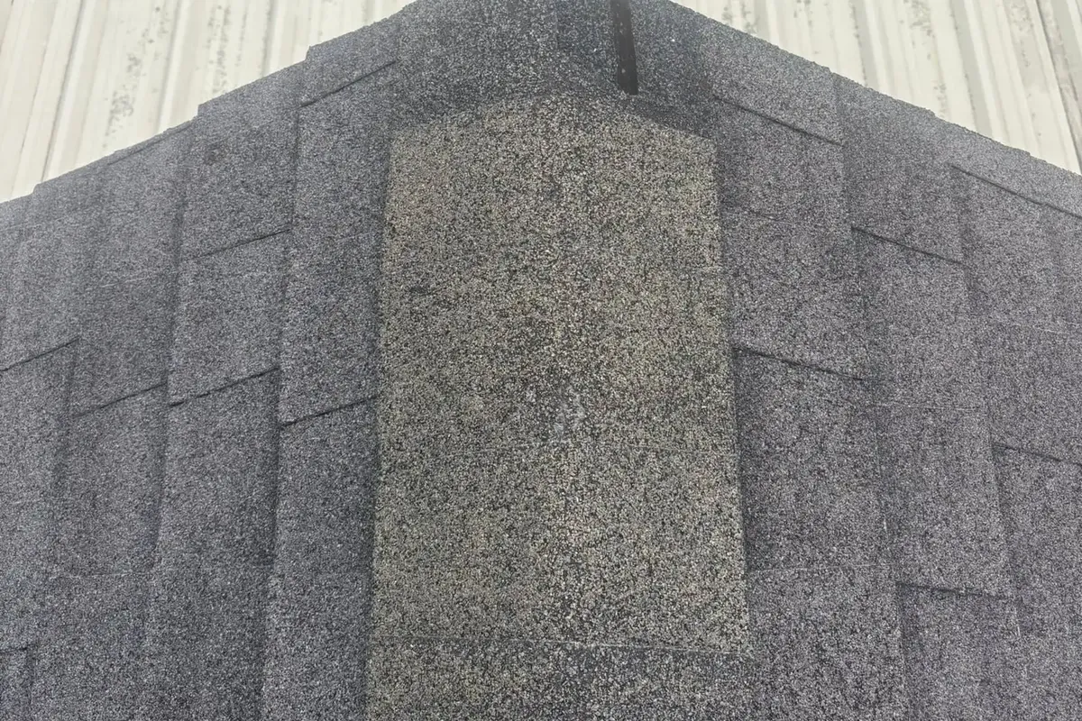 Dark shingle ridge cap with metal roof behind, C&A Roofing & Construction