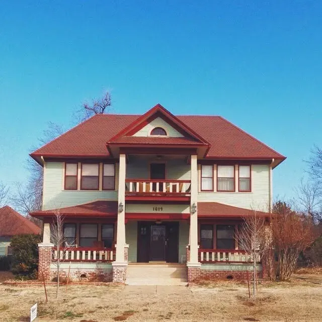 Two-story historic light green house with red shingle roof, C&A Roofing & Construction