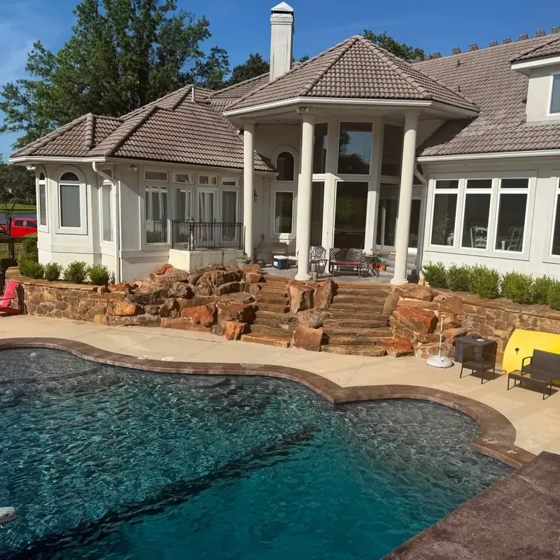 Stucco custom home with brown tile roof behind pool, C&A Roofing & Construction