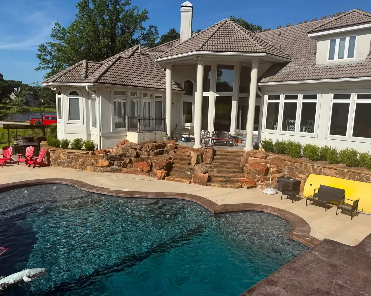 Stucco custom home with brown tile roof behind pool, C&A Roofing & Construction
