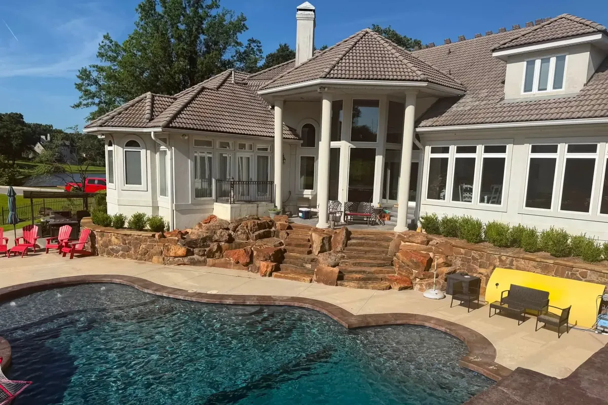 Stucco custom home with brown tile roof behind pool, C&A Roofing & Construction