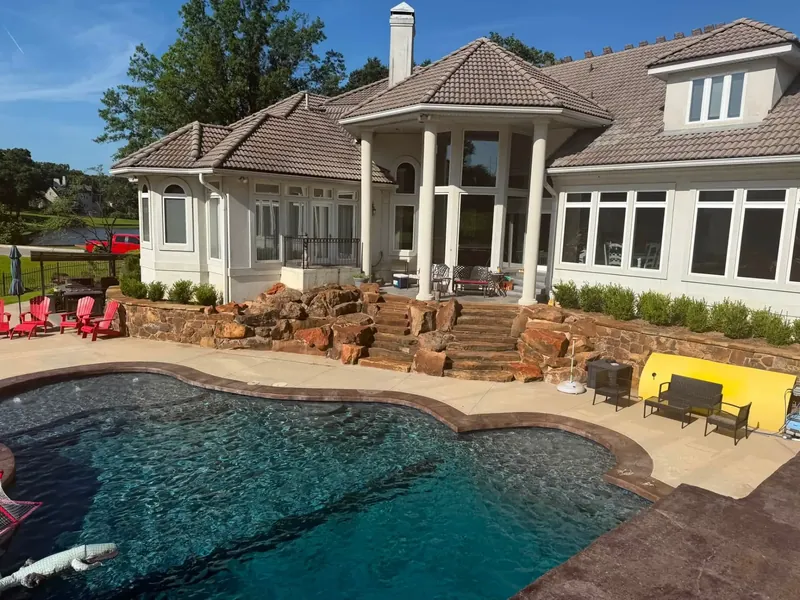 Stucco custom home with brown tile roof behind pool, C&A Roofing & Construction