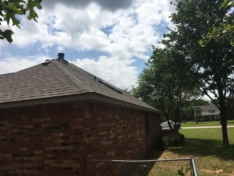 Corner of brick house with new shingle roof and vent, C&A Roofing & Construction