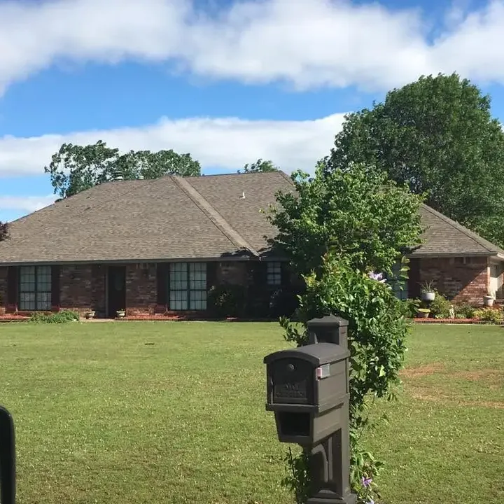 Brick ranch with shingle roof seen across lawn, C&A Roofing & Construction