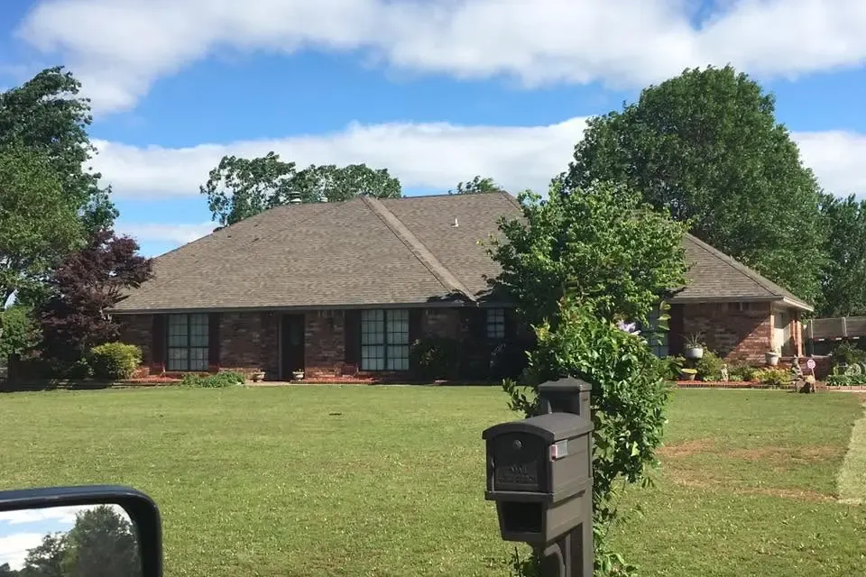 Brick ranch with shingle roof seen across lawn, C&A Roofing & Construction