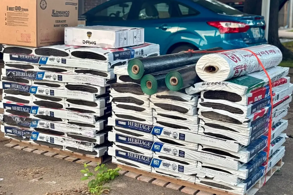 Pallets of shingle bundles and underlayment under carport, C&A Roofing & Construction