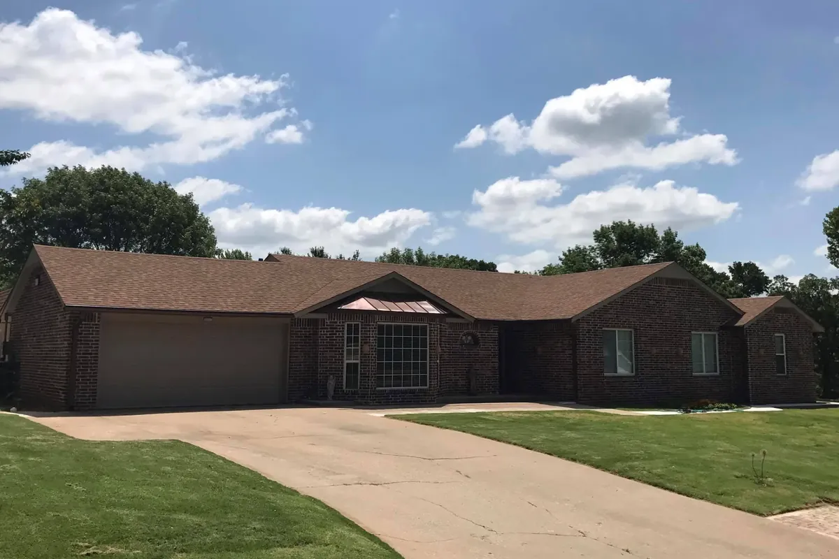Long brick ranch with brown shingle roof and driveway, C&A Roofing & Construction