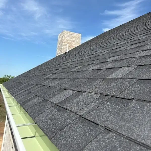 Dark gray shingles along gutter with chimney, C&A Roofing & Construction