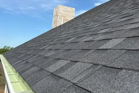 Dark gray shingles along gutter with chimney, C&A Roofing & Construction