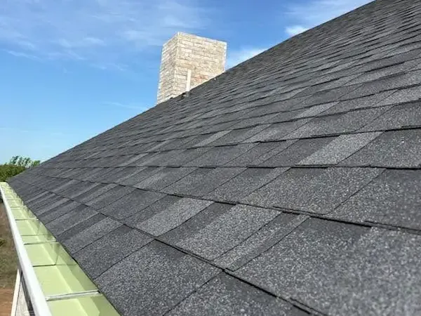 Dark gray shingles along gutter with chimney, C&A Roofing & Construction