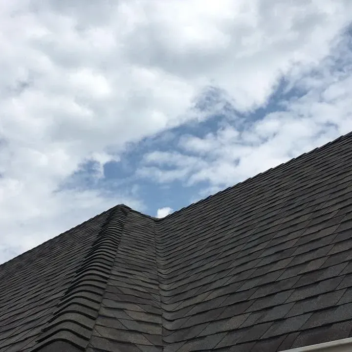 Dark shingle roof ridgelines against cloudy sky, C&A Roofing & Construction