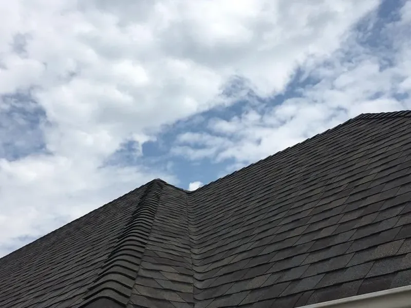 Dark shingle roof ridgelines against cloudy sky, C&A Roofing & Construction