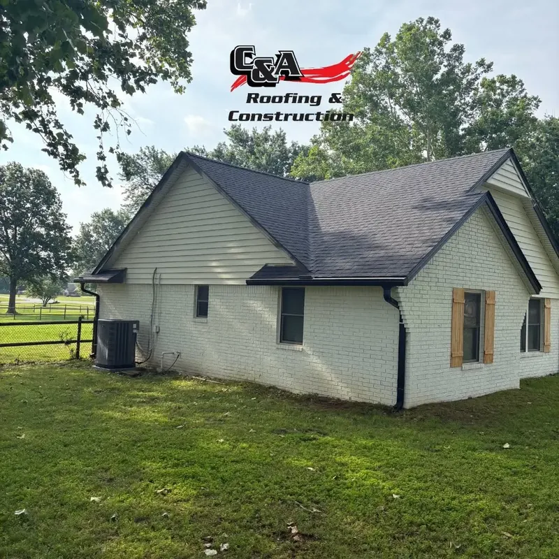 White farmhouse with new dark shingle roof, C&A Roofing & Construction