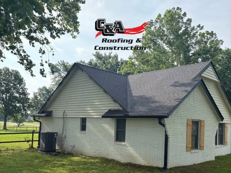 White farmhouse with new dark shingle roof, C&A Roofing & Construction