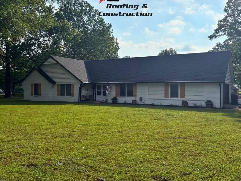 White ranch house with dark shingle roof across lawn, C&A Roofing & Construction