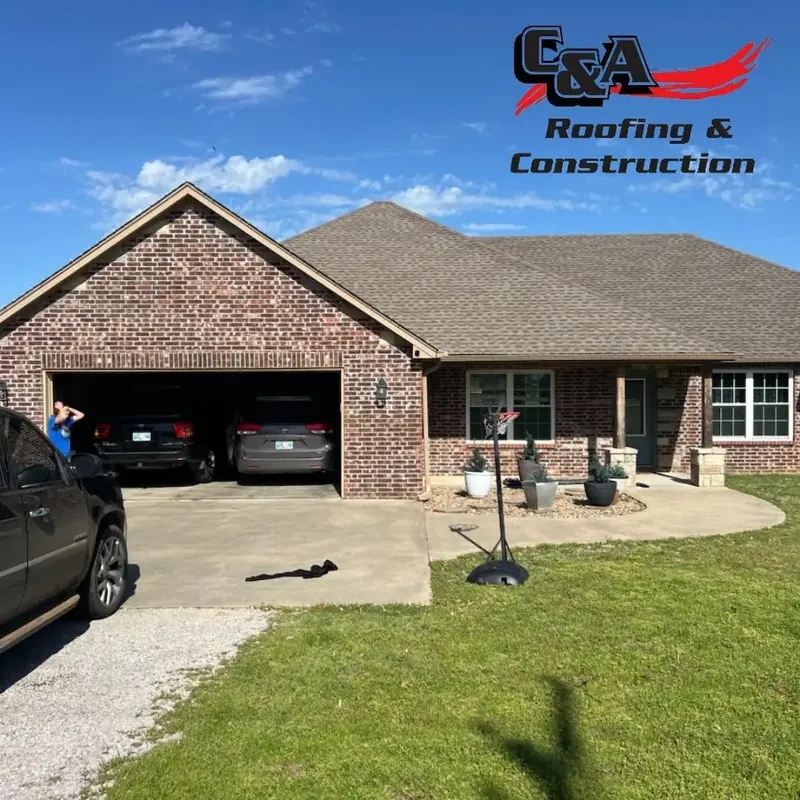 Brick house with brown shingle roof and open garage, C&A Roofing & Construction